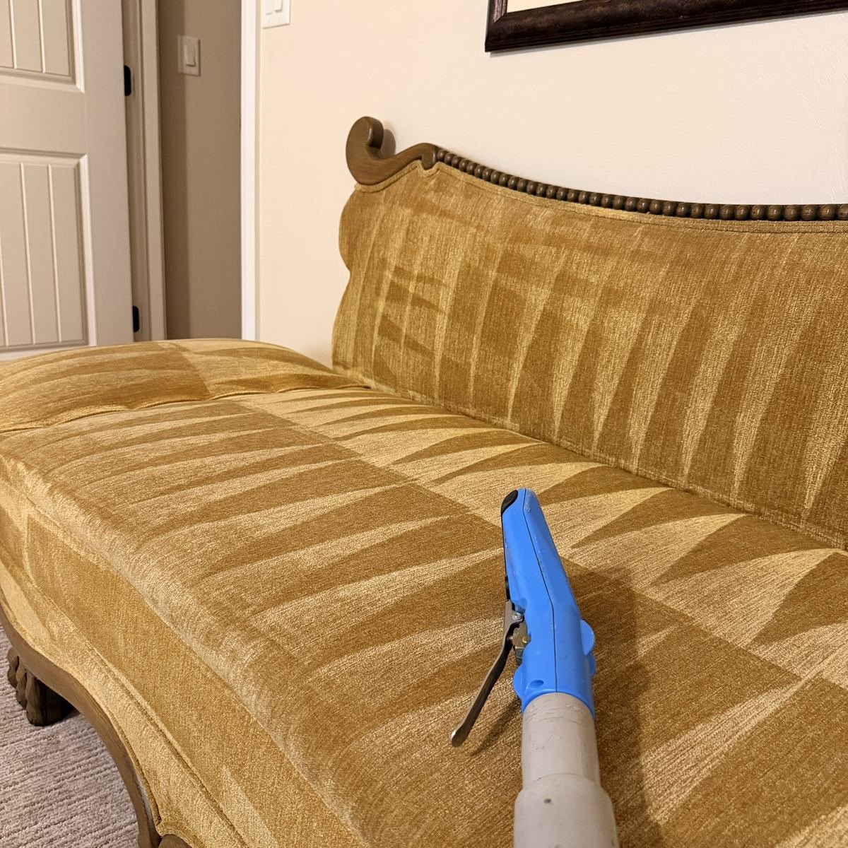 Low-moisture extraction wand treating the cushions of a vintage chenille sofa mid-clean